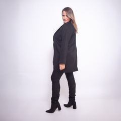 Saco Siberia negro, modelo luciendo el abrigo de lado, combinando con pantalones y botas negras.