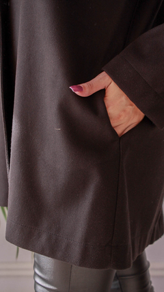 Detalle de un saco siberiano negro con una mano en el bolsillo, mostrando el tejido suave y elegante.