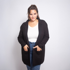 Saco Victoria negro de mujer, con bolsillos, sobre una blusa blanca y jeans, posando frente a un fondo blanco.