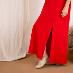 Vestido largo rojo con abertura lateral, visto desde la parte inferior y acompañado de calzado ligero.