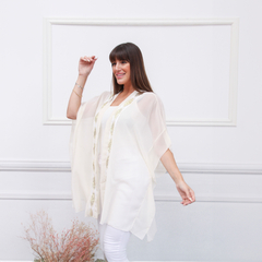 Modelo usando un spolverino blanco con detalles dorados, posando con una mano levantada y una sonrisa.