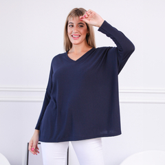 Modelo luciendo un sweater Ambar de color azul marino con escote en V y mangas largas, posando con una mano levantada.