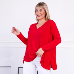 Modelo luciendo un sweater rojo de manga larga con escote en V, combinado con pantalones blancos.