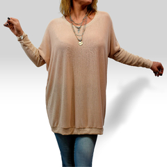 Modelo usando un suéter Dafne de color nude, con pantalones jeans y accesorios de joyería.