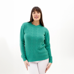 Modelo usando un suéter verde con textura de trenzas, de manga larga y cuello redondo.