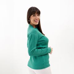 Modelo sonriente usando un suéter verde Eleo con textura de canalé.