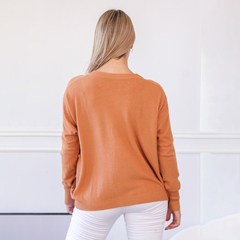 Vista trasera de un sweater color naranja, modelo Elfi, sobre fondo claro.