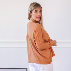 Sweater Elfi en color naranja, modelo posando de perfil con cabello rubio y fondo blanco.