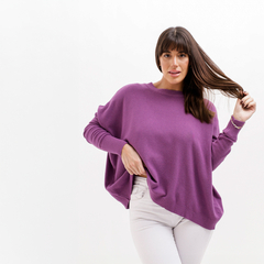 Modelo luciendo un suéter morado llamado Elfi, con mangas amplias, sobre un fondo blanco.