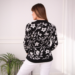Suéter Flow negro con diseño floral blanco, visto desde atrás, con mujer de cabello largo y lacio.