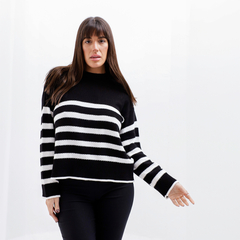 Modelo vistiendo un sweater de rayas en blanco y negro, con mangas largas y un diseño moderno.