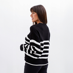 Modelo usando un sweater de rayas negras y blancas, visto desde el costado.