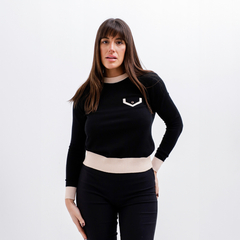 Modelo usando un sweater negro con detalles en beige y un diseño de bolsillo en el pecho.