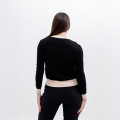 Mujer de espaldas usando un sweater negro con detalles en beige.