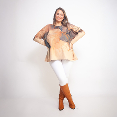 Mujer sonriente posando con sweater Napoles de manga larga con diseño de hojas en tonos beige y marrón, combinado con pantalón blanco y botas marrones