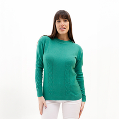 Suéter verde con diseño trenzado, modelo femenino, usado con pantalones blancos.