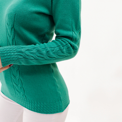 Sweater verde con detalles de trenzas en las mangas y el borde, ajustado al cuerpo.
