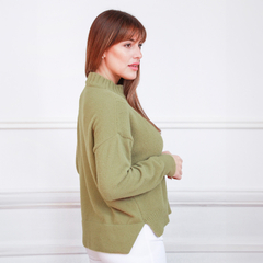 Mujer con suéter verde oliva, de perfil, en un fondo blanco.
