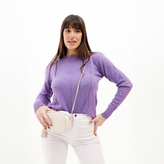 Modelo luciendo un sweater de color púrpura con detalles en relieve y un bolso claro.