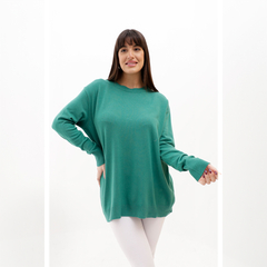 Mujer posando con un sweater verde, de manga larga y corte amplio, en fondo blanco.