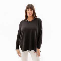 Modelo vistiendo un sweater negro con detalles dorados en el escote y los laterales.