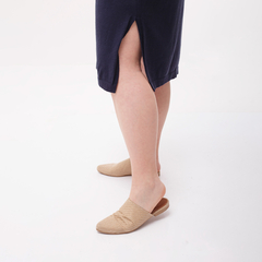Vista de una túnica oscura con una abertura lateral, combinada con zapatos de color beige.