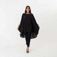 Túnica Sol con aplique en color negro, modelo de mujer posando con pantalones oscuros y sandalias, destacando la fluidez de la prenda.
