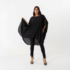 Túnica negra con aplique brillante, modelo posando en un fondo blanco.