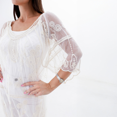 Túnica Winter de color blanco, con bordados florales y mangas transparentes, modelo en una pose elegante.
