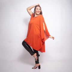Túnica Sol Perla naranja elegante para fiesta, con diseño suelto y mangas abiertas, combinada con pantalones negros y sandalias de tacón