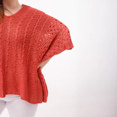 Poncho Venus de color coral con diseño de tejido abierto, ideal para abrigarse con estilo.