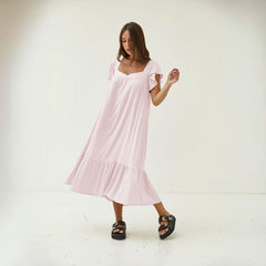 Vestido Aire de color rosa claro, con mangas cortas y falda amplia, modelado por una mujer en un fondo neutro.