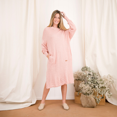 Vestido Anquet de color rosa, con mangas largas y bolsillos, presentado en un ambiente acogedor.