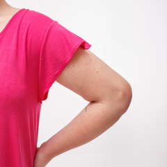 Detalle de un vestido básico rosa, mostrando la parte superior y un brazo.