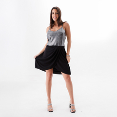 Modelo posando con un vestido negro y top brillante, adecuado para ocasiones elegantes.