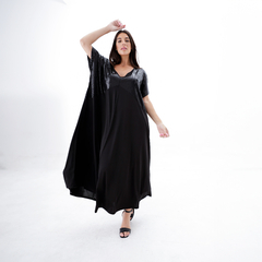 Vestido largo negro con detalles brillantes en la parte superior, modelo caminando sobre un fondo blanco.
