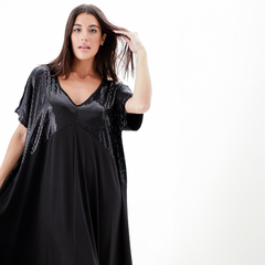 Vestido largo negro con detalles brillantes en la parte superior, modelo posando y tocándose el cabello.