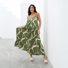 Vestido largo de color verde con estampado ondulado, modelo Derek, usado por una mujer en un entorno minimalista.