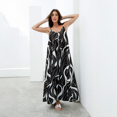 Vestido largo negro y blanco con estampado de ondas, modelo Derek, lucido por una mujer en un ambiente moderno.