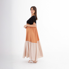 Modelo luciendo un vestido largo de dos tonos, con parte superior negra y falda en tonos terracota y beige.