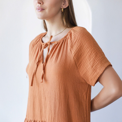Vestido Gaier de color naranja con detalles de lazo en el escote, con mangas cortas y textura suave.