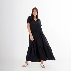 Modelo posando con un vestido largo negro de estilo casual, con mangas cortas y falda amplia.