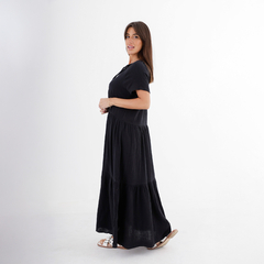 Modelo usando un vestido largo negro con mangas cortas y un diseño de volantes.
