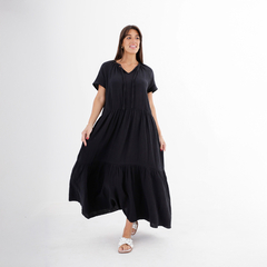 Modelo luciendo un vestido largo negro con detalles en la parte inferior.