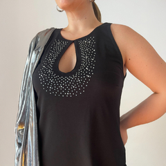Vestido negro sin mangas con detalle de strass en el escote y un abrigo plateado sobre el hombro.