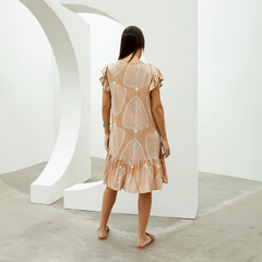 Vista trasera del vestido Isadora con estampado de hojas en tonos beige, modelo con mangas rizadas y falda con volantes.