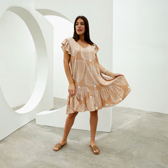 Vestido Isadora con estampado de hojas, modelo de manga corta y falda con volantes, luciendo en un entorno moderno.