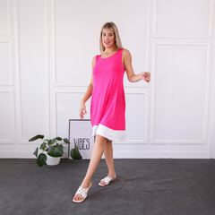 Modelo luciendo un vestido rosa brillante con detalles en blanco, en un ambiente luminoso y moderno.