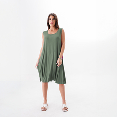 Modelo usando un vestido verde sin mangas, con un diseño fluido, en un fondo blanco.