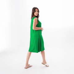 Modelo luciendo un vestido verde brillante, con una caída fluida, caminando sobre fondo blanco.